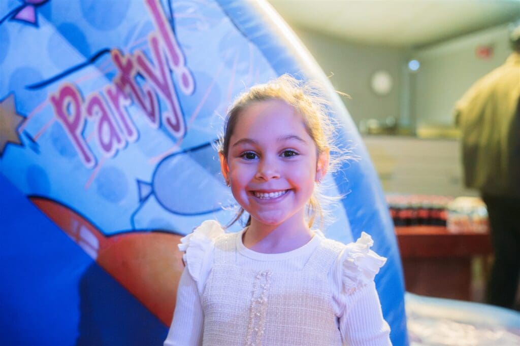 A birthday girl beaming in front of the party bouncy castle at Vibe