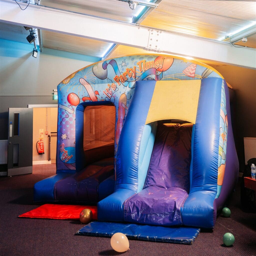 The 'It's Party Time' bouncy castle and slide set up in the party room